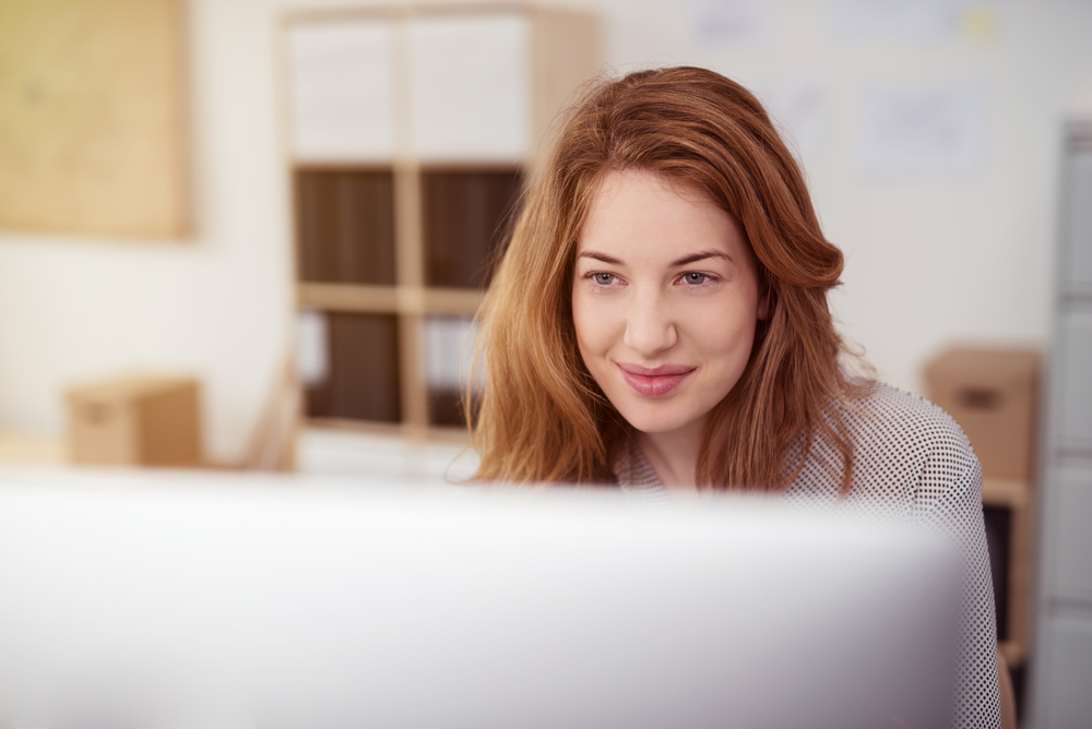 woman smiling while working on her computer