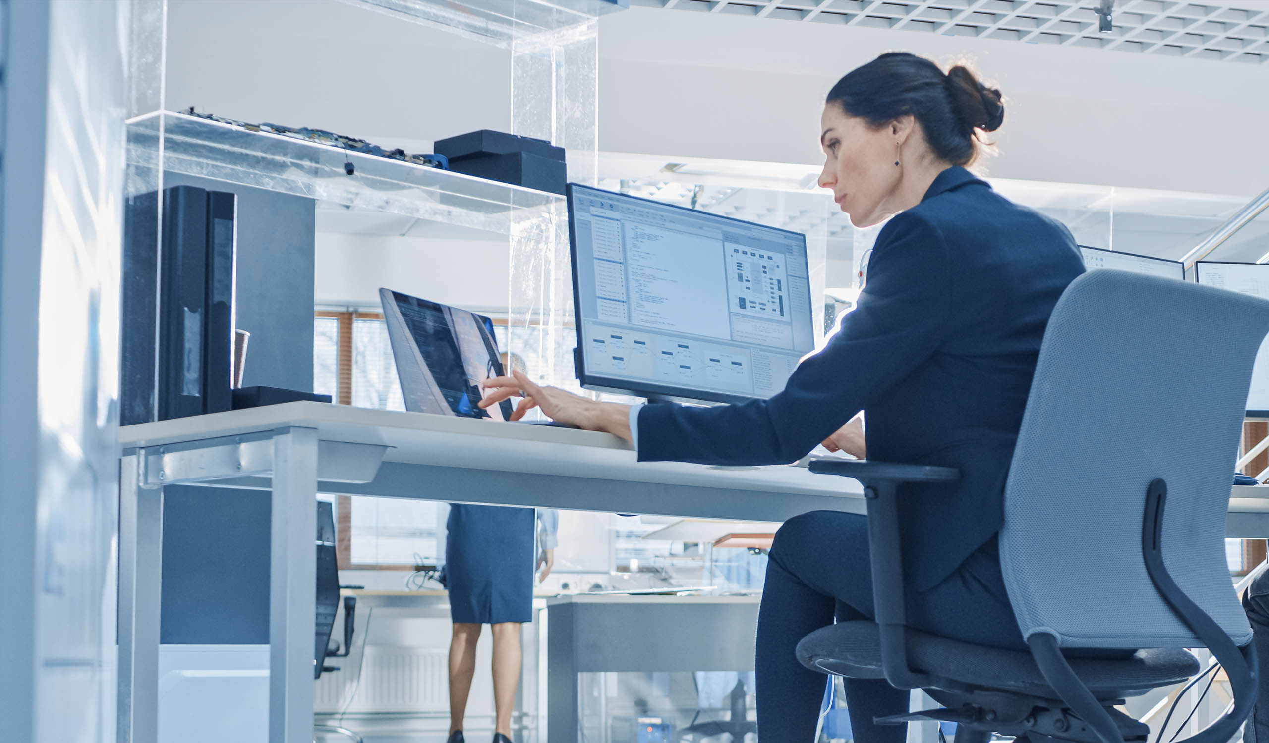 Woman reviewing information on her computer and her tablet