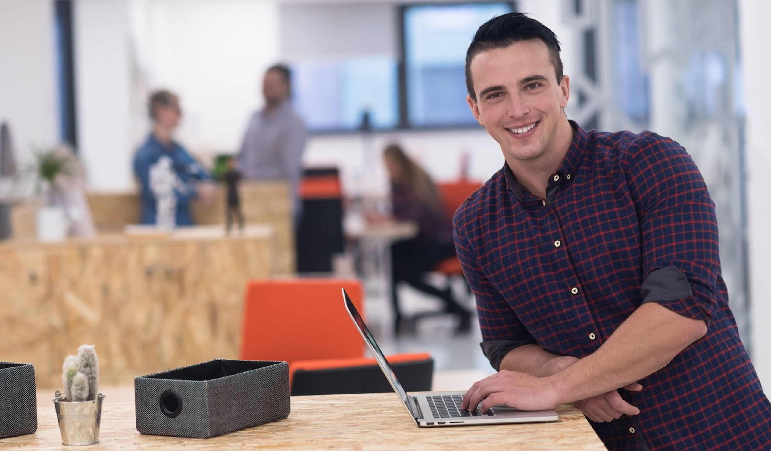 Man smiling while using his laptop at the office